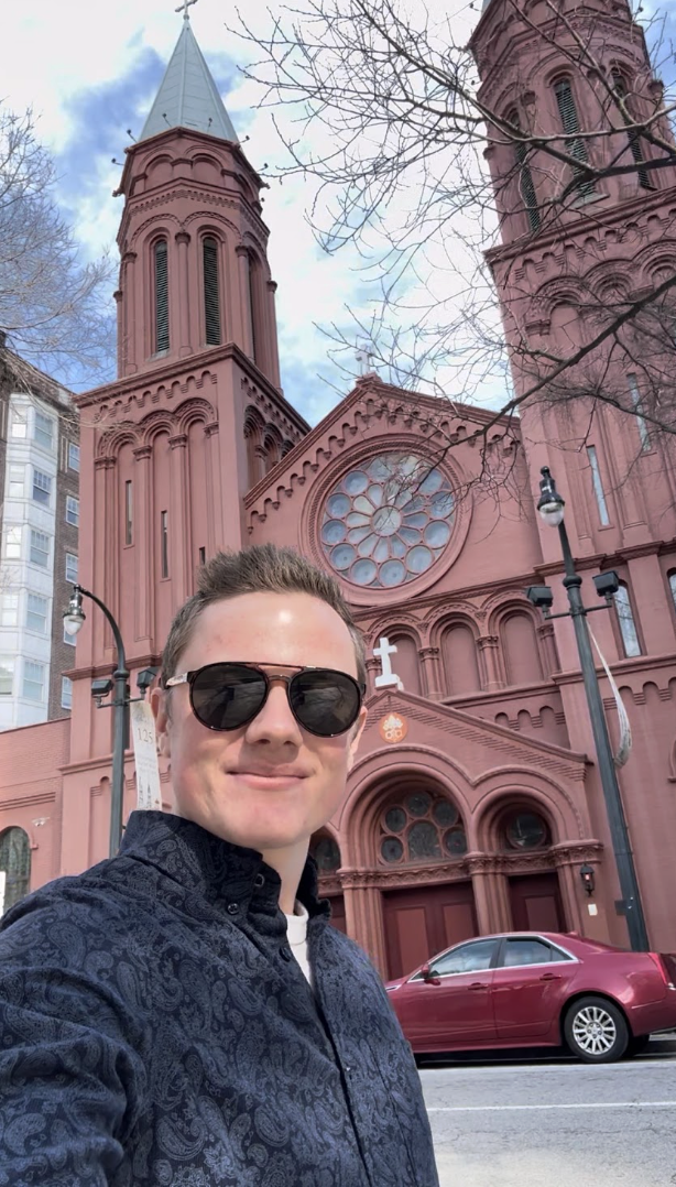 Grady Connolly in front of a basilica with twin towers and a rose window
